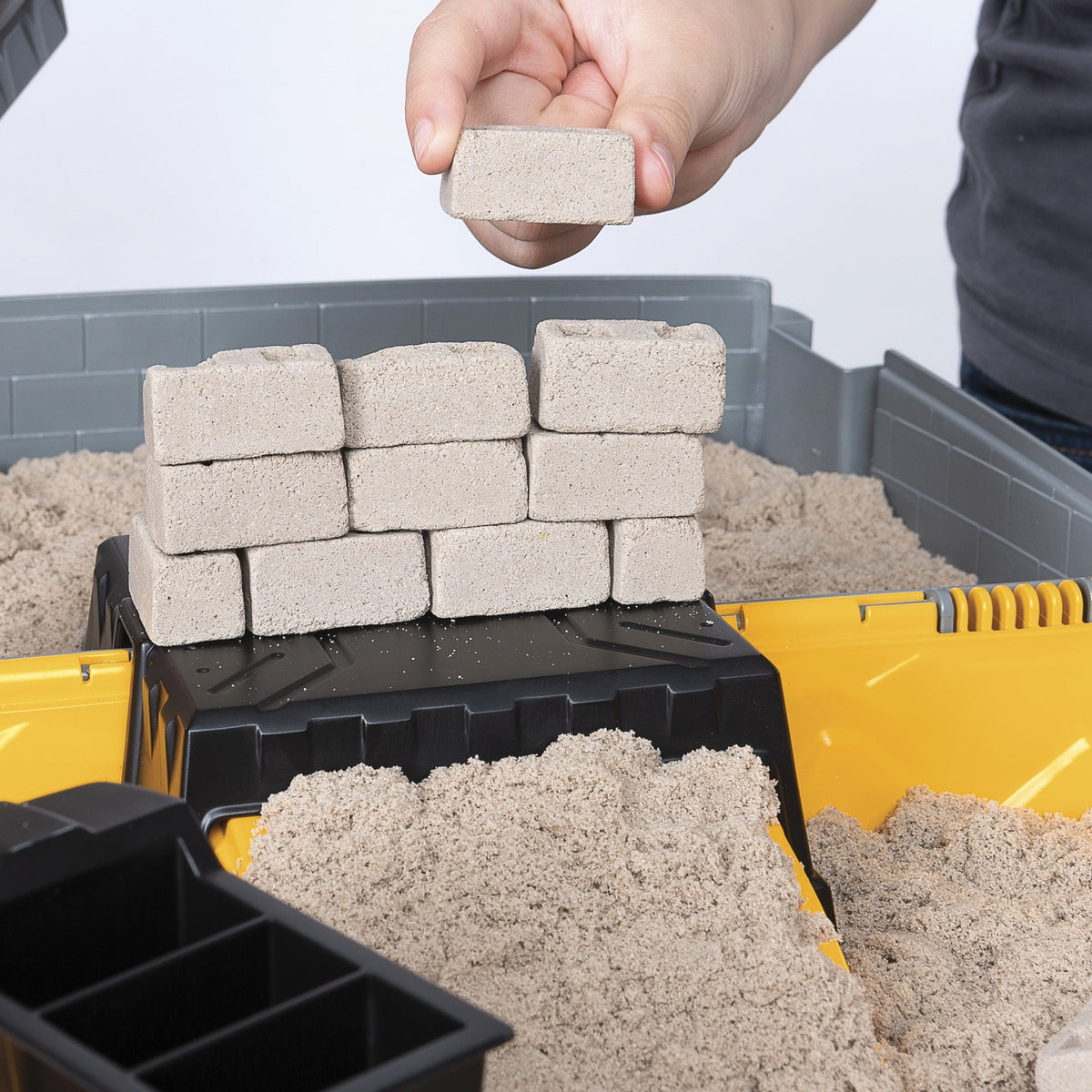 Barn bygger væg af sandsten med Kinetic Sand legetøj