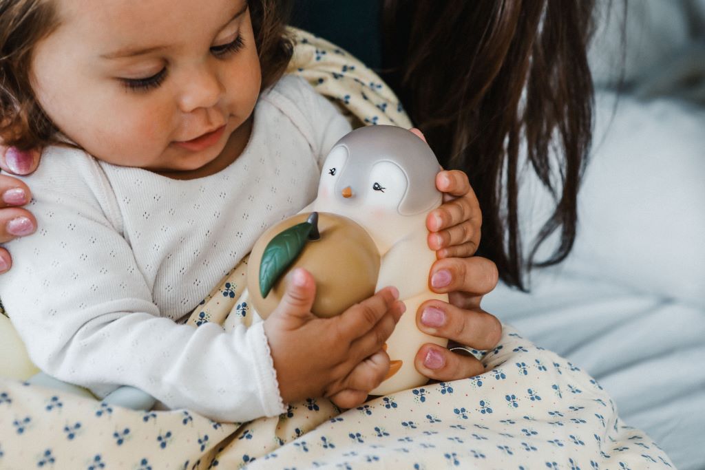 Baby holder en sød pingvin-legetøj, der giver lys.