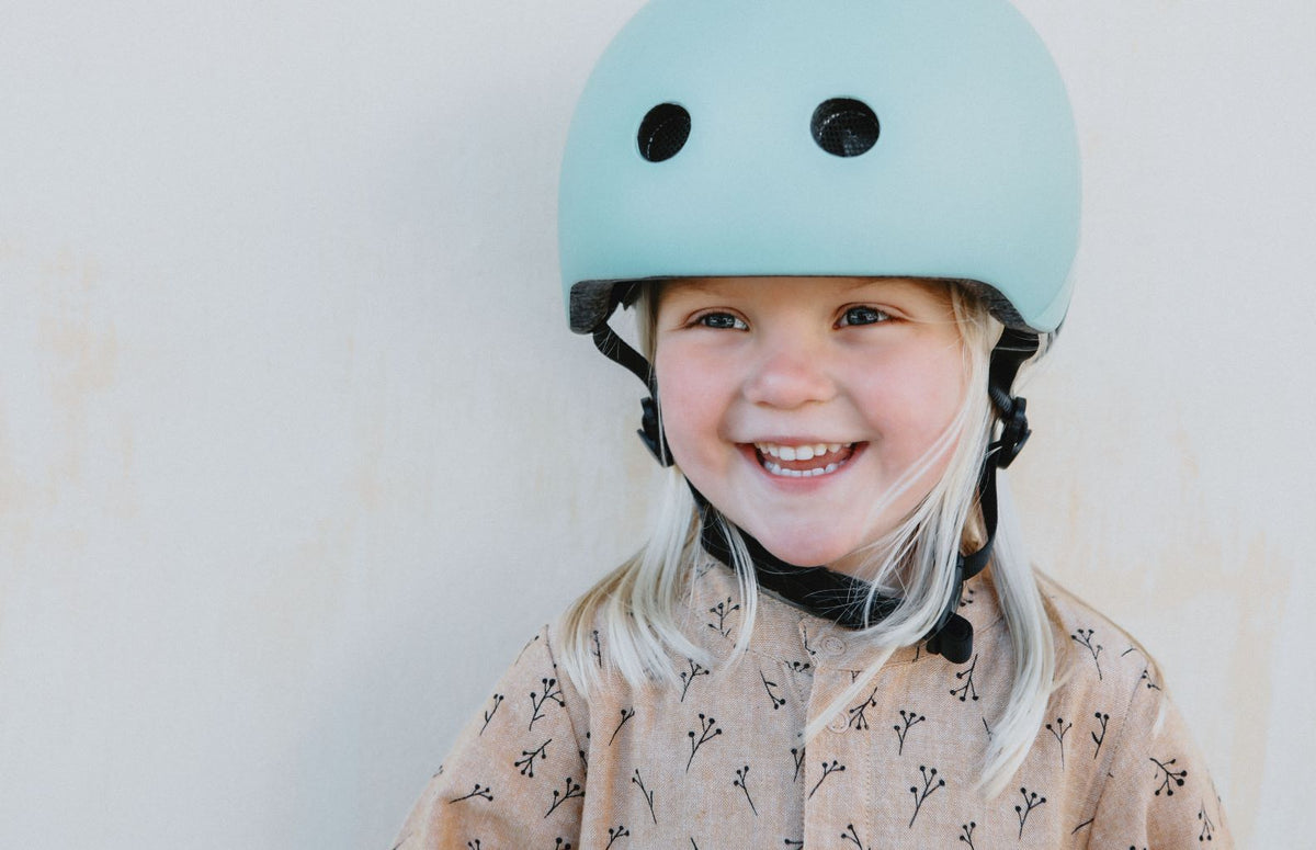 Glimende blond barn iført en mintgrøn cykelhjelm.
