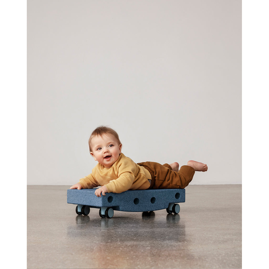 Baby på Modu rullebræt i dybblå/himmelblå farve, smiler og leger