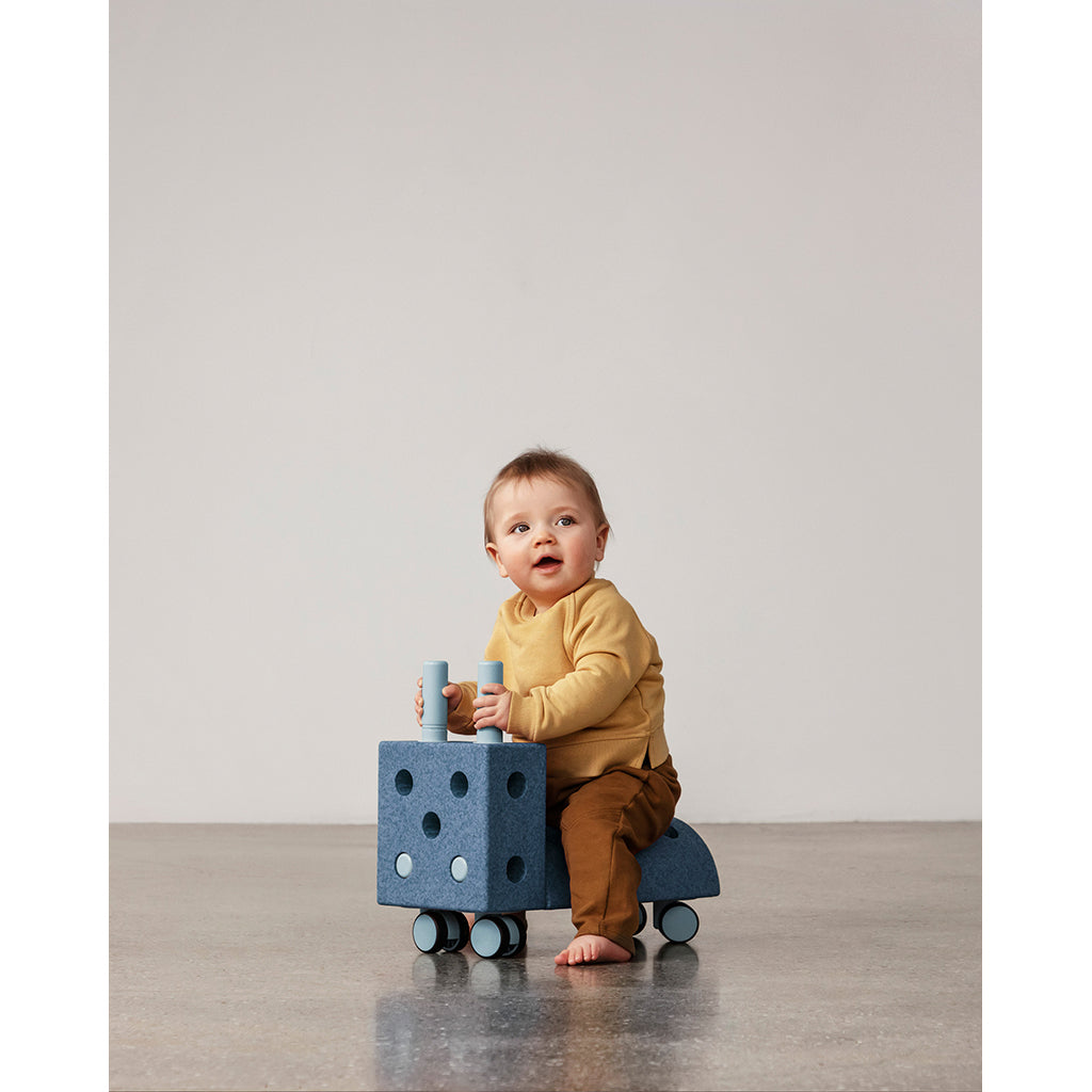 Baby sidder på Modu Tiny Ride aktivitetslegetøj i blå